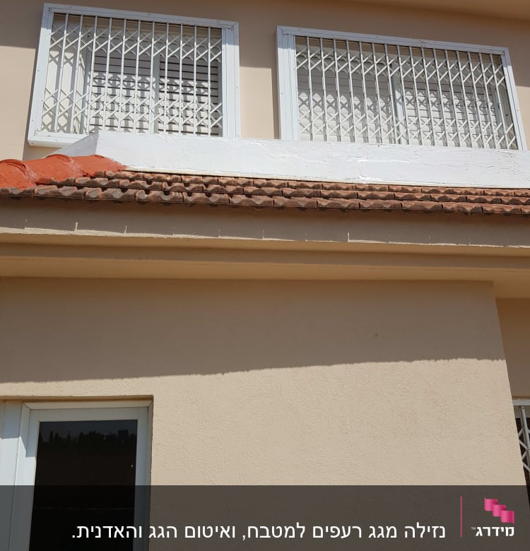 רעפים חומים על גג בית עם קיר לבן